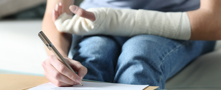 a person writing on a table with one hand in cast on their lap personal injury civardi obiol